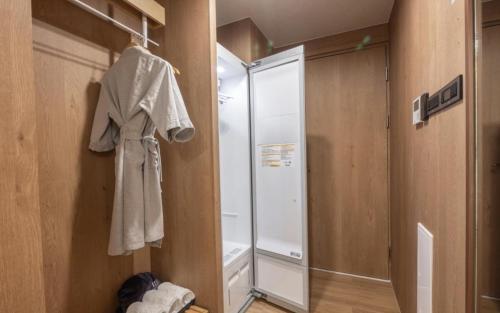 a bathroom with a shower and a robe hanging on a wall at H-Avenue Hotel Haeundae in Busan