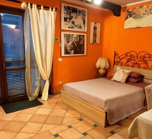 a bedroom with orange walls and a bed and a window at B&B Vista su Roma in Marco Simone