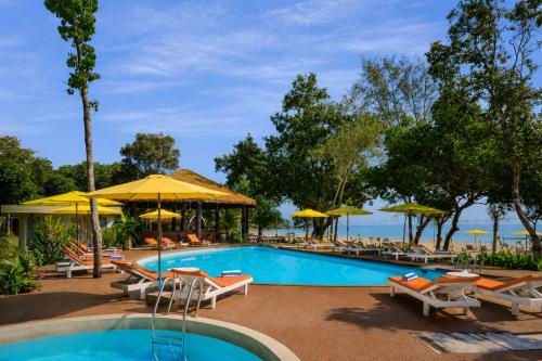a swimming pool with tables and chairs and umbrellas at Sandy Beach Bungalows by EHM in Koh Rong Sanloem