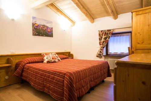 a bedroom with a bed with a red bedspread at Hotel Restaurant La Barme in Cogne