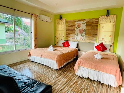 a bedroom with two beds and a couch and a window at แสงหิรัญ บีช รีสอร์ท in Pran Buri