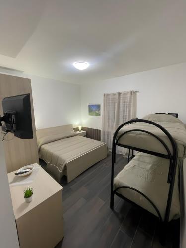 a bedroom with two bunk beds and a television at Affittacamere Sisca Oriolo in Schiavonea