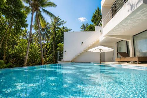 a swimming pool with an umbrella next to a house at The Seven Stars Resort in Ishigaki Island