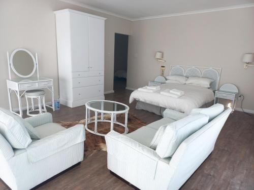 a bedroom with two beds and two chairs and a table at Ripples Beach House - 14 sleeper in Port Alfred