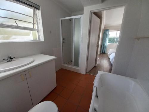 a bathroom with a sink and a toilet and a mirror at Ripples Beach House - 14 sleeper in Port Alfred