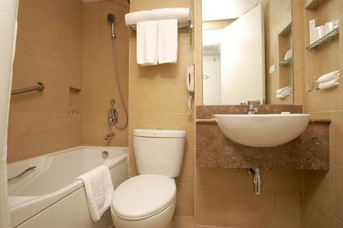 a bathroom with a toilet and a sink and a tub at St Giles Hotel Makati in Manila