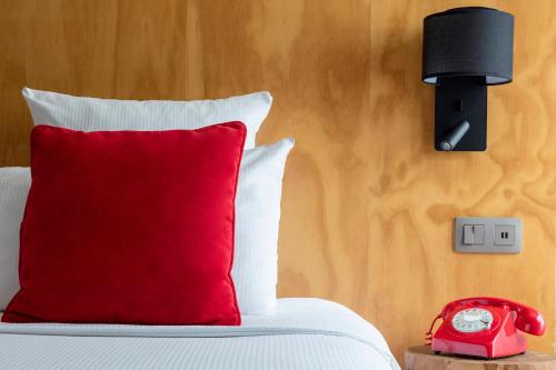 a bed with a red pillow and a alarm clock at Hôtel Les Aiglons Chamonix in Chamonix