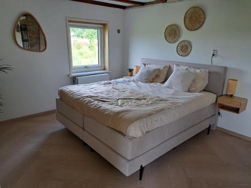 a large bed in a bedroom with a window at Onder de regenboog in Egmond aan den Hoef