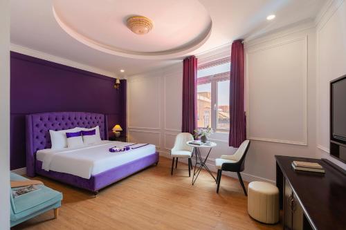 a bedroom with a purple bed and a table and chairs at Peach Valley Hotel Dalat in Da Lat