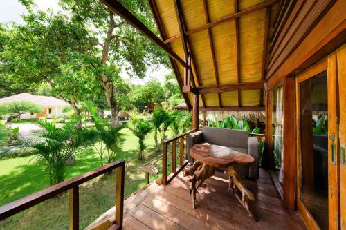 a porch of a house with a table and a chair at Kaia Raya Surf Lodge in Maluk