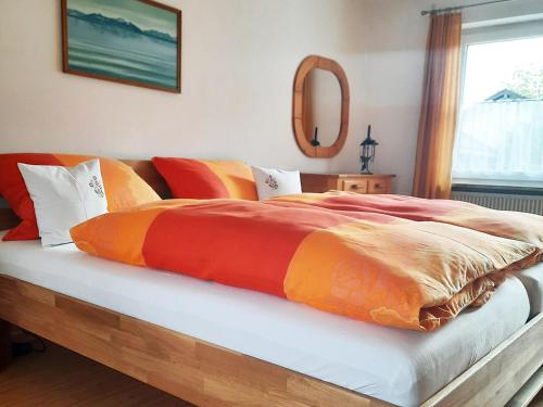 a bed with an orange and orange blanket on it at Ferienwohnung Mutzenbauer in Bad Endorf