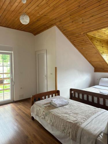 a bedroom with two beds and a wooden ceiling at Guesthouse HYSA in Valbonë