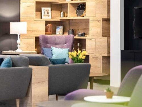 a living room with a couch and chairs and a clock at Mercure Budapest City Center in Budapest