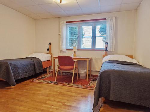 a bedroom with two beds and a desk and a window at EFS-gården in Åsljunga