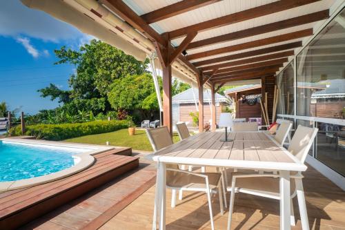 a patio with a table and chairs next to a swimming pool at Villa Le Nid des Colibris in Gourbeyre