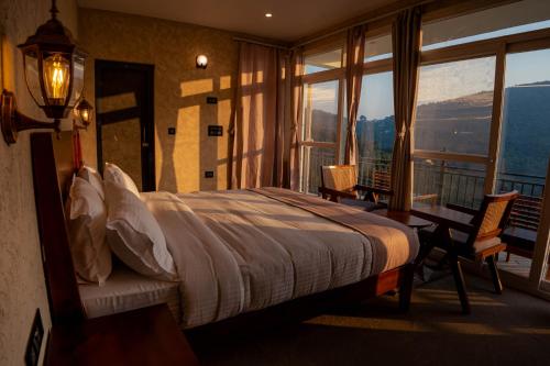 a bedroom with a bed and a balcony with a view at Enchanted Hills Farmstay in Mukteshwar