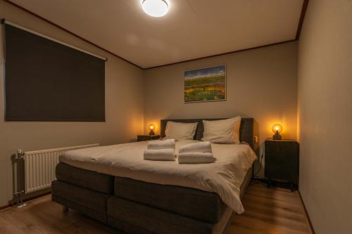 a bedroom with a large bed and a flat screen tv at Grasheide: Modern in Drenthe (4p) in Erm