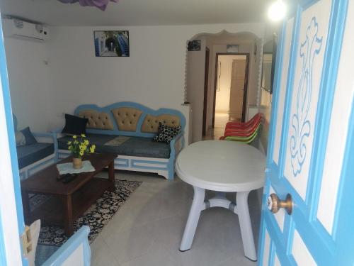 a living room with a blue couch and a stool at Studio Yakina in El Haouaria