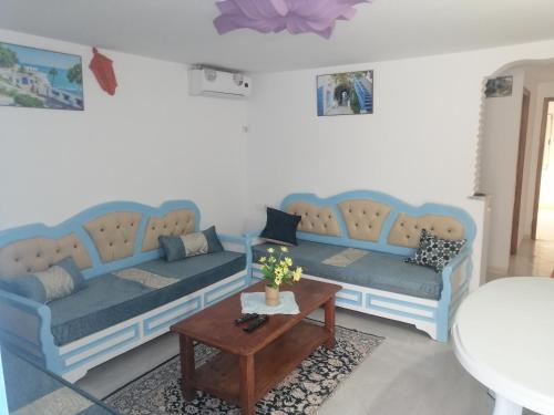 a living room with two blue couches and a table at Studio Yakina in El Haouaria