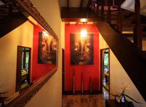 a hallway with red walls and a staircase with a face on the wall at 7 Bedroom Seafront Villa Phangan SDV232-By Samui Dream Villas in Srithanu