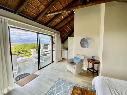 a bedroom with a bed and a balcony with a view at i-LOLLO Bed & Breakfast at the River Mouth in St Francis Bay