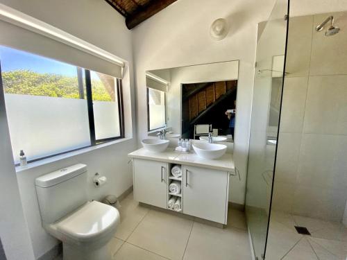 a bathroom with a toilet and two sinks and a shower at i-LOLLO Bed & Breakfast at the River Mouth in St Francis Bay