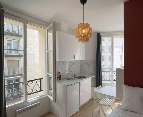 a white kitchen with a sink and a window at Hôtel My Suite Paris in Paris
