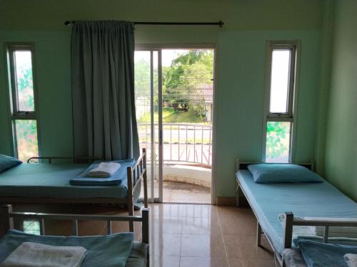 a room with two beds and a window at มังกรเลโฮสเทล Mangkonlay Hostel in Ban Khlong Pak