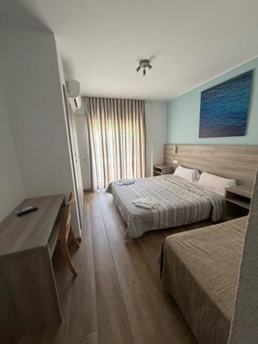a hotel room with two beds and a desk at Pensió Costa Brava in Sant Antoni de Calonge