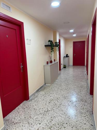 a hallway with red doors and a tile floor at Pompei Sanctuary rooms in Pompei