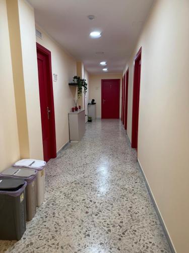 an empty hallway with red doors and trash cans at Pompei Sanctuary rooms in Pompei