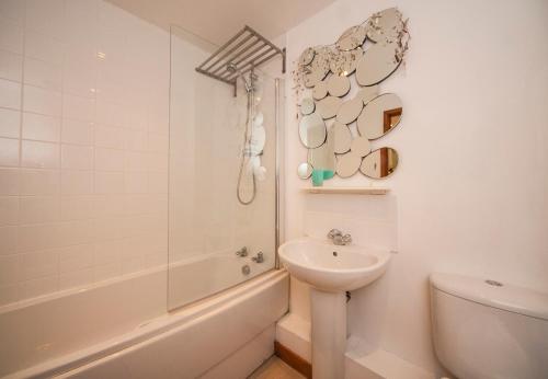 a bathroom with a sink and a tub and a toilet at White Lodge Apartments in Mawgan Porth
