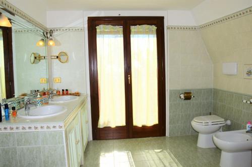 a bathroom with two sinks and a toilet and a door at B&B Sedici Pini in Pomezia