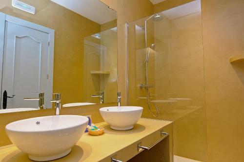 a bathroom with two sinks and a glass shower at Family Agua Amarga in Agua Amarga