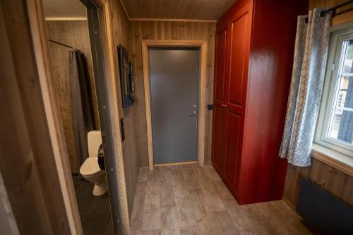 a bathroom with a toilet and a red door at Karstenstua in Holo