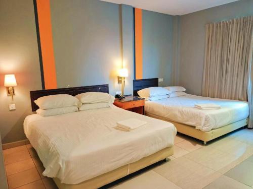 two beds in a hotel room with two lamps at One World Lodging in Bentong