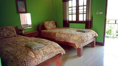 a bedroom with two beds and green walls at Baanraimaetha Resort in Bān Phea