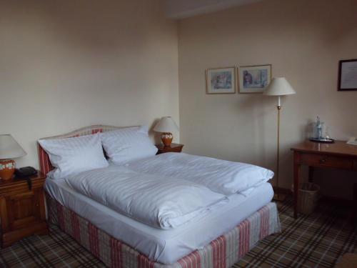 um quarto com uma cama com lençóis brancos e 2 candeeiros em Hotel Freihof em Wiesloch