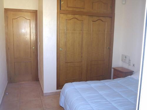 een slaapkamer met een bed en 2 houten kasten bij Gran Alacant Apartment in Puerto Marino
