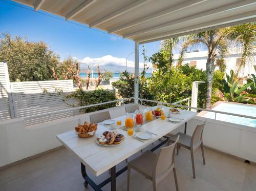 a white table with food on it on a balcony at CasaSol Deluxe villa sulla Spiaggia con Piscina e Jacuzzi By Sicily Home Solutions in Alcamo