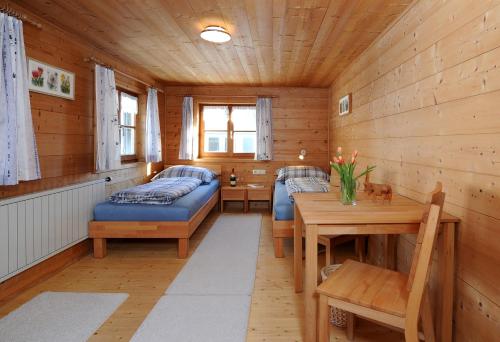 Zimmer mit 2 Betten und einem Tisch in einer Hütte in der Unterkunft Ferienwohnungen Moosbrugger in Au im Bregenzerwald