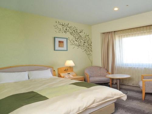 a hotel room with a bed and a window at Rihga Royal Hotel Niihama in Niihama