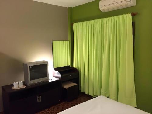 a bedroom with a green wall with a tv and a bed at Baan Chomphu in Prachuap Khiri Khan