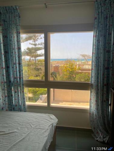 a bedroom with a bed and a large window at Alshrooq Village 97 in Borg El Arab