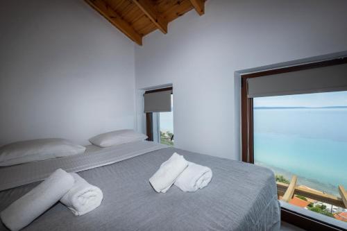 a bedroom with a bed with pillows and a large window at Grande Blu by NG Villas in Afitos