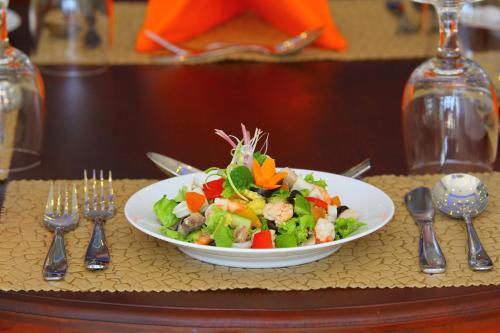 a salad in a white bowl on a table with silverware at Saffron Hotel Unawatuna in Unawatuna