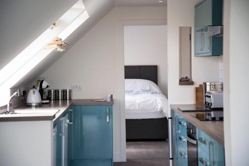 a kitchen with blue cabinets and a bed at Dun Caan Apartment in The Braes