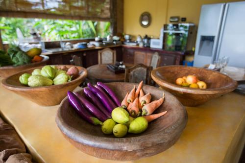 a counter with bowls of fruits and vegetables on it at DWan Tea Mountain Side in Jatiluwih