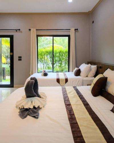 two beds in a room with two large windows at S Garden View Resort in Ban Bang Yai Chuai