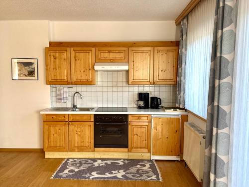a kitchen with wooden cabinets and a stove top oven at Ferienwohnungen Billovits in Kössen